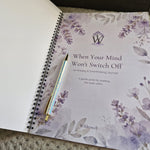 An open spiral-bound journal showing the cover page titled "When Your Mind Won't Switch Off: An Anxiety & Overthinking Journal" with floral watercolor artwork in soft purple and gray tones. A metallic iridescent pen rests on the cover.